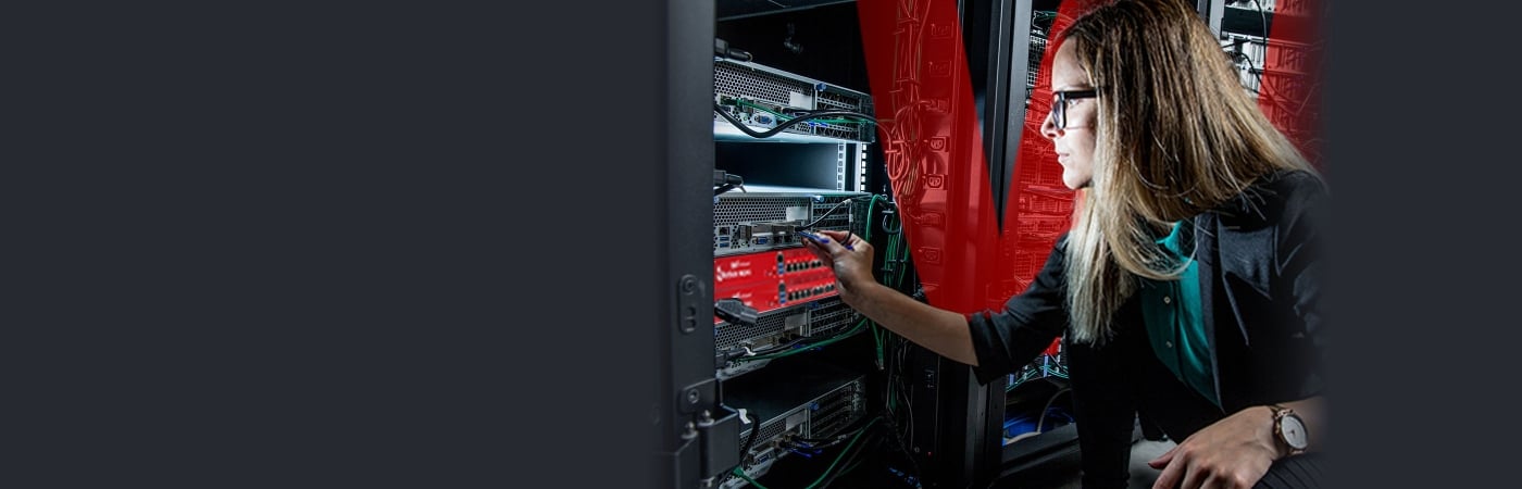 Blonde woman reaching for a red WatchGuard Firebox in a server rack