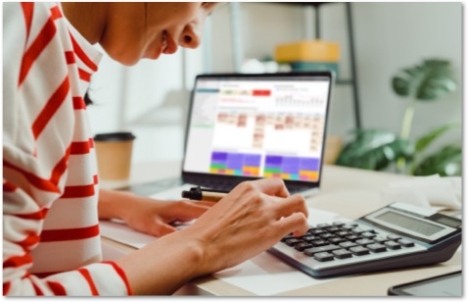 smiling woman working on a laptop and calculator