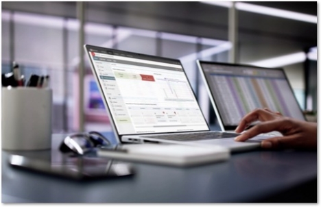 two laptops side by side showing charts and WatchGuard Cloud dashboards