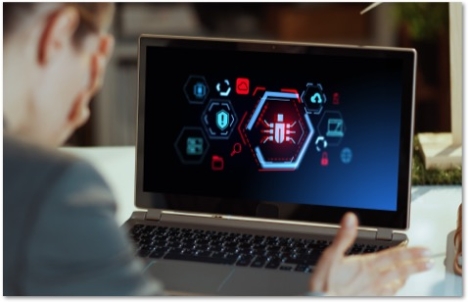 Man with his hand over his face and a laptop showing virus icons on the screen