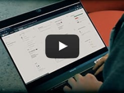 Video screenshot of a person using a laptop showing a WatchGuard Cloud screen