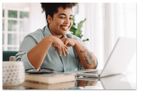Smiling woman looking at a laptop screen in an airy white room